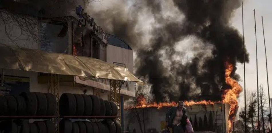 Un hombre corre tras sacar cosas de una tienda en llamas luego de un ataque ruso en Járkiv, Ucrania, el 25 de marzo de 2022. ap