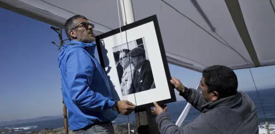 Trabajadores colocan un retrato del poeta chileno Pablo Neruda con el expresidente Salvador Allende en la tumba del bardo, en Isla Negra, Chile, el 26 de abril de 2016. AP