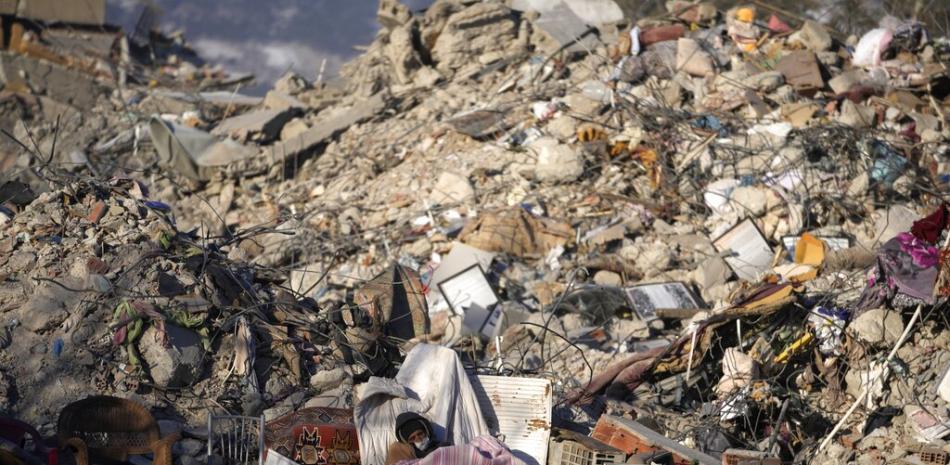 Un hombre duerme frente a un edificio destruido en Kahramanmaras, sureste de Turquía, el lunes 13 de febrero de 2023. AP