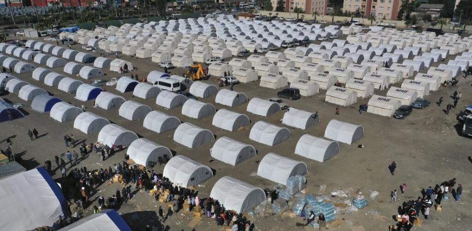 Personas que perdieron sus hogares en el terremoto que sacudió Turquía y Siria se forman para recibir ayuda en un campamento improvisad, | AP