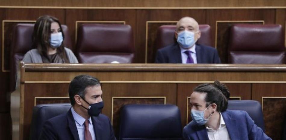 El presidente del gobierno de España, Pedro Sánchez (izquierda), y el vicepresidente segundo, Pablo Iglesias, hablan durante una sesión parlamentaria en Madrid, el 21 de octubre de 2020. AP