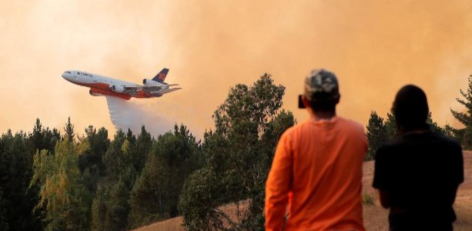 Un lugareño toma instantáneas cuando un avión de bomberos 10 Tanker DC-10 arroja agua sobre un incendio forestal en Quirihue, Región de Ñuble, en Chile, el 10 de febrero de 2023. Los incendios forestales se han prolongado durante más de una semana en el centro-sur de Chile, dejando al menos 24 personas muertas.
JAVIER TORRES / AFP