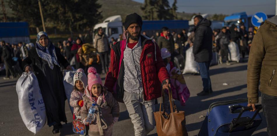 Sirios ingresan a su país desde el punto de cruce turco de Cilvegozu, en Reyhanli, sureste de Turquía, el sábado 18 de febrero de 2023, casi dos semanas después del fatal sismo. (Foto AP/Bernat Armangue)
