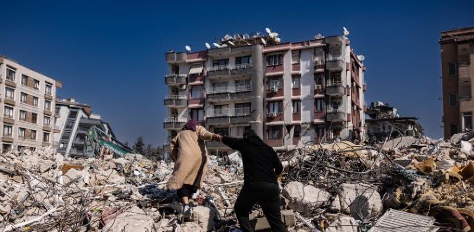 Una pareja escala los escombros de los edificios derrumbados en Antakya, al sur de Turquía, el 20 de febrero de 2023. Un terremoto de magnitud 7,8 golpeó cerca de Gaziantep, Turquía, en las primeras horas del 6 de febrero, seguido de otro temblor de magnitud 7,5 poco después del mediodía. Sameer Al-DOUMY / AFP