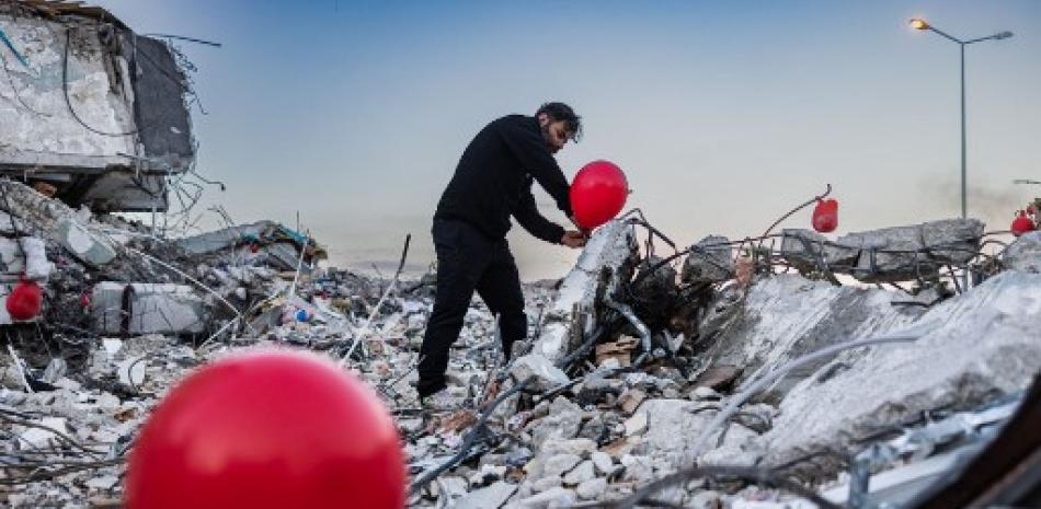 Ogun Sever Okur, turco de 38 años, infla globos sobre los escombros de un edificio derrumbado en Antakya, al sur de Turquía, el 21 de febrero de 2023, tras el terremoto de magnitud 6,4 que se produjo el 20 de febrero, dos semanas después de un terremoto de magnitud 7,8 terremoto golpeó cerca de Gaziantep y ha matado a más de 44.000 personas. En el costado de una carretera transitada en Antakya, docenas de globos rojos revolotean, colgando de las ruinas. Fotos AFP
