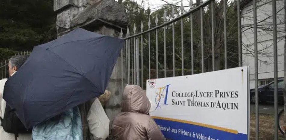 Personas frente a una escuela católica privada donde una maestra fue muerta a puñaladas el miércoles 22 de febrero de 2023 en Saint-Jean-de-Luz. AP