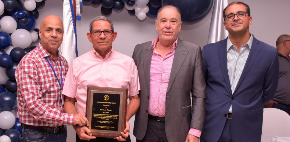 El entrenador de natación del Club Naco, Radhames Plácido, recibe una placa de reconocimiento luego de anunciar su retiro tras más de 40 años laborando en el club.