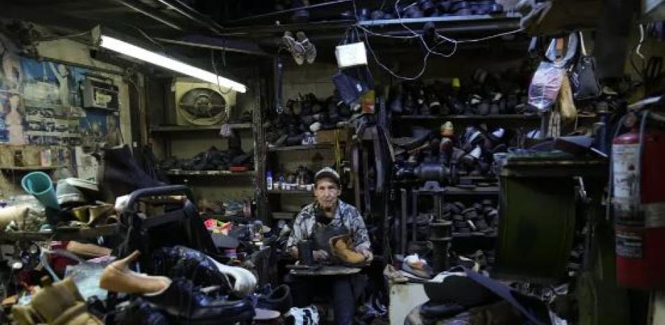 José Francisco Rodríguez, zapatero desde hace 46 años, posa para la foto en su taller de reparación de calzado en Caracas, 24 de febrero de 2023. Dice que tiene "fe en Venezuela" y jamás emigraría, aunque reconoce que puede tomar esa decisión porque tiene un negocio establecido. (Foto AP)