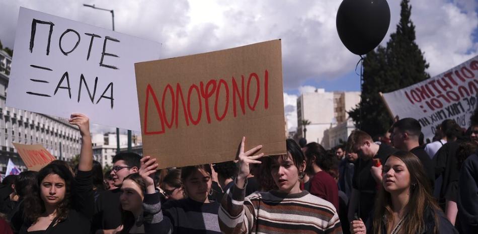 Varias personas sostienen pancartas que dicen "Asesinos" y "Nunca más", durante una protesta frente al Parlamento griego por el reciente choque de dos trenes, el domingo 5 de marzo de 2023, en Atenas. (AP Foto/Aggelos Barai)