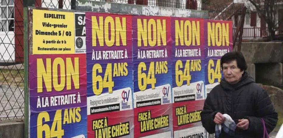 Una mujer pasa junto a carteles que dicen “No a la jubilación a los 64” en Saint Pee sur Nivelle, en el suroeste de Francia,  ayer. AP