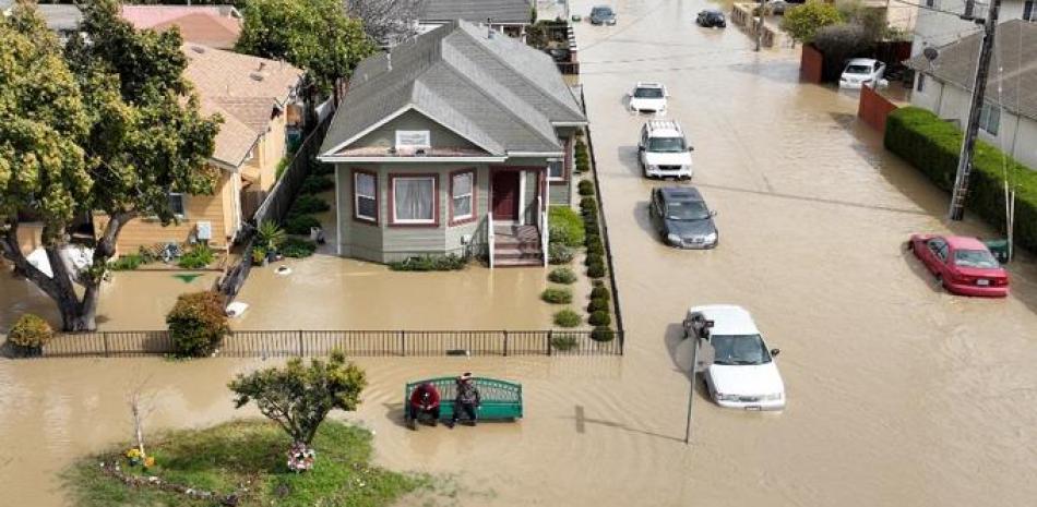 Una vista aérea muestra a personas sentadas en un banco en un barrio inundado en la comunidad no incorporada de Pájaro en Watsonville, California, el 11 de marzo de 2023. Foto: AFP.