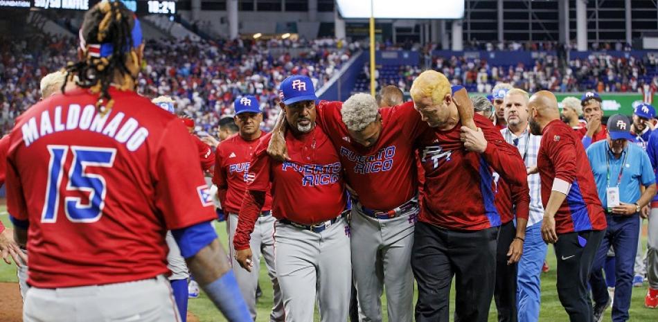 El pitcher puertorriqueño Edwin Díaz (39) recibe auxilio del coach Ricky Bones y el personal médico tras lesionarse en un juego contra la República Dominicana.