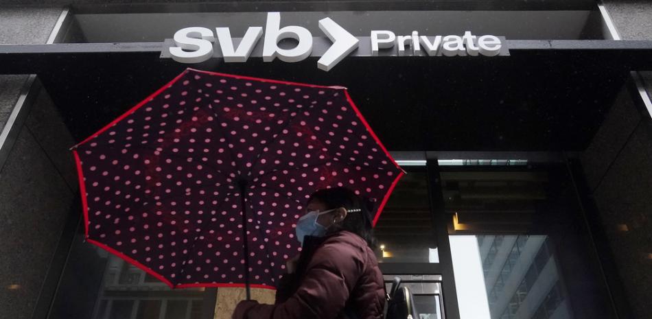 Un peatón lleva un paraguas mientras pasa frente a una sucursal privada de Silicon Valley Bank en San Francisco, el martes 14 de marzo de 2023. (Foto AP/Jeff Chiu)