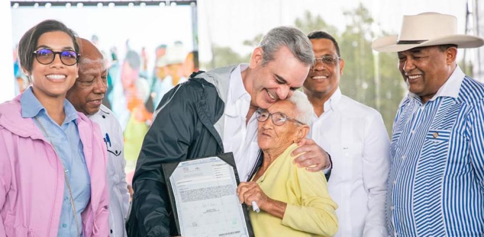 El presidente Luis Abinader entrega el título de propiedad a una señora de la comunidad El Pocito, durante un acto realizado ayer en Monte Cristi. Onelio Domínguez