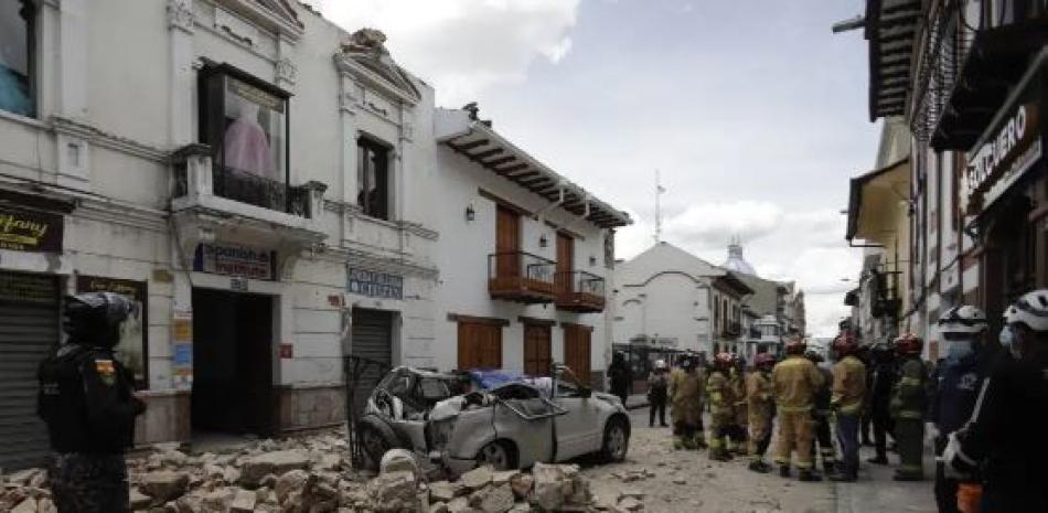 Rescatistas junto a un automóvil aplastado por los escombros tras un terremoto en Cuenca, Ecuador, el sábado 18 de marzo de 2023. (Foto AP)