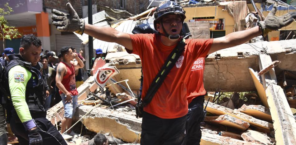 Varios socorristas buscan sobrevivientes entre los escombros tras la caída de un inmueble por un fuerte sismo en Machala, Ecuador, el sábado 18 de marzo de 2023. (AP Foto/Jorge Sanchez)