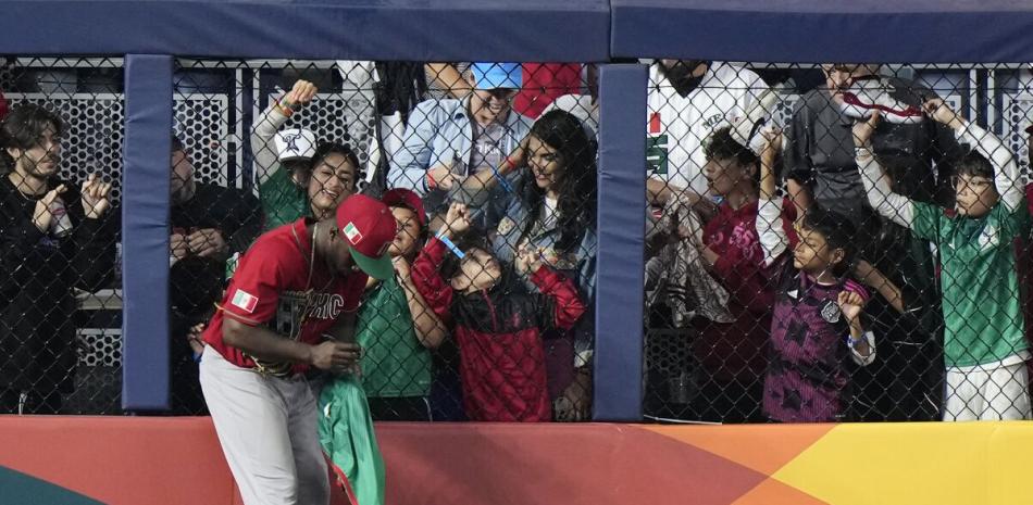 El jardinero de México Randy Arozarena firma autógrafos durante un cambio de lanzadores en el séptimo inning de la semifinal contra Japón en el Clásico Mundial.