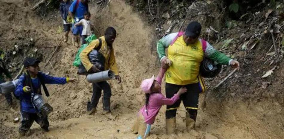 Una mujer trata de levantar a una niña de un paso enlodado mientras migrantes ecuatorianos atraviesan la selva del Darién para llegar desde Colombia a Panamá en su ruta hacia Estados Unidos, el 15 de octubre de 2022. AP