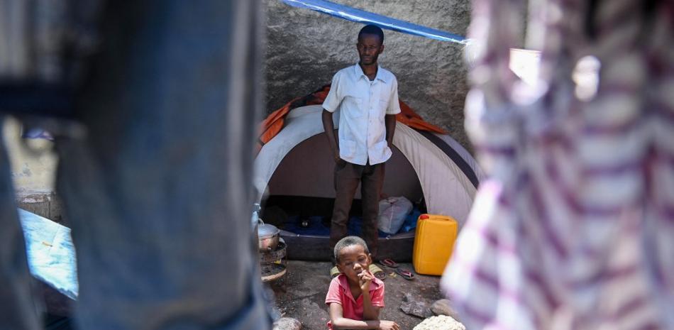 Tervile Eliuse, director de escuela y pastor de iglesia, se para frente a su tienda de campaña con su hijo en un campamento de refugiados improvisado establecido por personas que escapan de la actividad de las pandillas en la comuna Delmas 19 en Port-au-Prince, Haití, el 23 de marzo de 2023 , mientras las pandillas toman áreas de Haití.
Foto: Richard Pierrín/ AFP