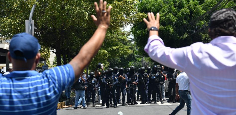 Dirigentes del Partido de la Liberación Dominicana levantan sus manos en señal de estar desarmados a los agentes policiales. JORGE LUIS MARTINEZ/LD