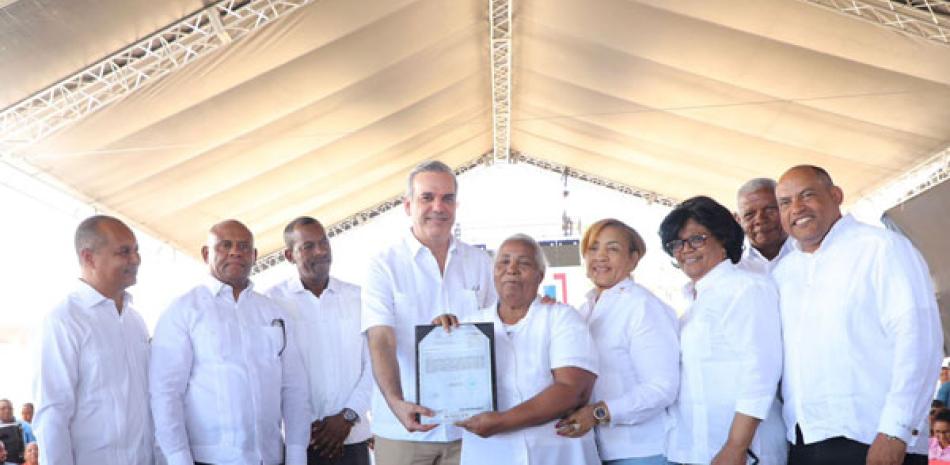 El presidente Abinader entrega uno de los 923 título de propiedad, a una señora de la comunidad de Tamayo.