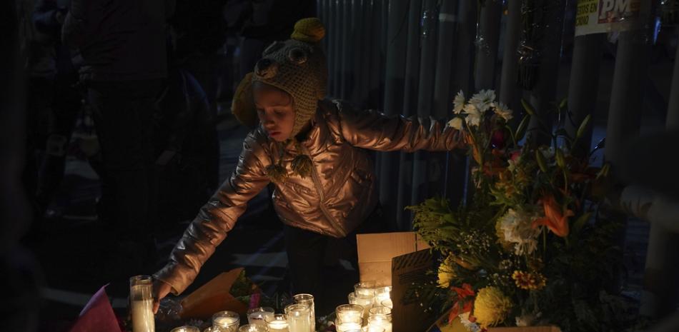 Una niña migrante venezolana enciende una vela durante una vigilia por las víctimas de un incendio en un centro de detención de inmigrantes que mató a decenas, en Ciudad Juárez, México, el martes 28 de marzo de 2023. Según el presidente mexicano Andrés Manuel López Obrador, los migrantes que temen ser deportados prender fuego a los colchones en el centro, iniciando el fuego. (Foto AP/Fernando Llano)