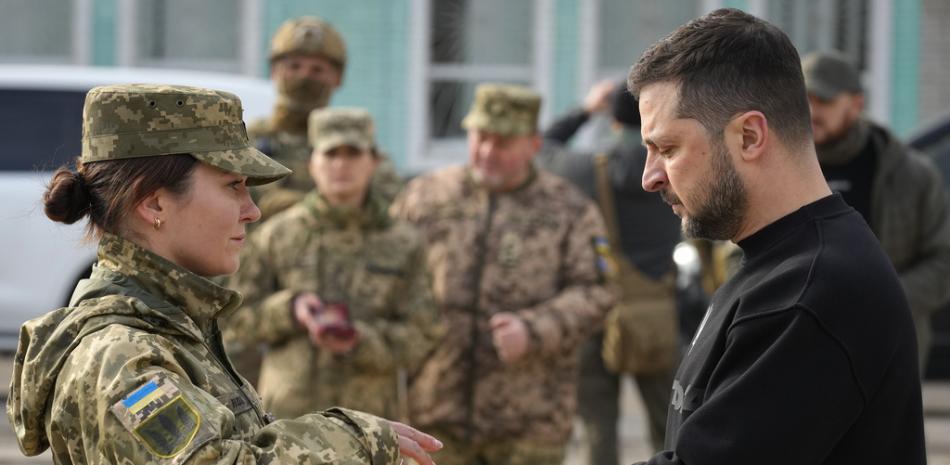 El presidente de Ucrania, Volodymyr Zelenskyy, entrega una medalla a una militar en Okhtyrka, en la región de Sumy, Ucrania, el martes 28 de marzo de 2023. AP