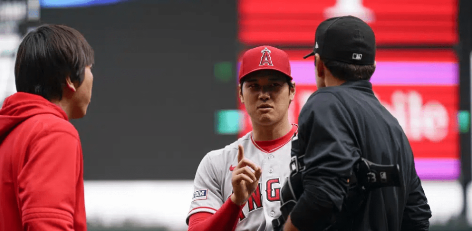 El lanzador abridor de los Angelinos de Los Ángeles, Shohei Ohtani, habla con el árbitro del plato Pat Hoberg después de la primera entrada de un juego de béisbol, en el que fue sancionado por una violación del reloj de lanzamiento contra los Marineros de Seattle. Miércoles, 5 de abril de 2023, en Seattle. (Foto AP/Lindsey Wasson)