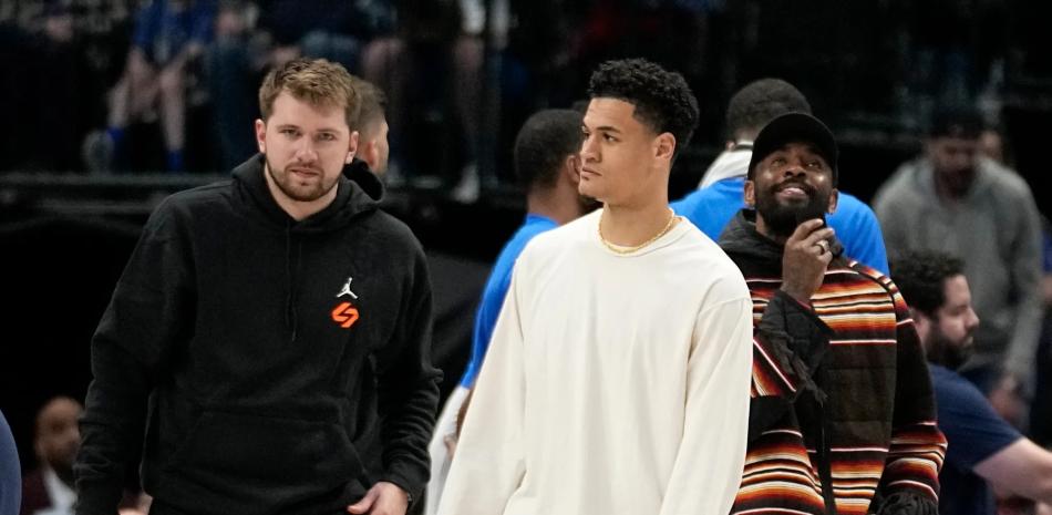 Luka Doncic, izquierda, Josh Green, centro, y Kyrie Irving, derecha, de los Dallas Mavericks, parados en la cancha durante un tiempo muerto en la segunda mitad de un partido de baloncesto de la NBA contra los Chicago Bulls, el viernes 7 de abril de 2023 en Dallas. (Foto AP/Tony Gutiérrez)