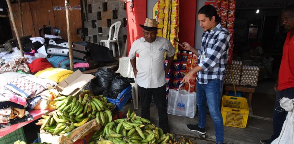 El periodista Sauro Scalella conversando con Lorenzo Roa, vendedor de plátanos en el mercadito de Los Alcarrizos. Foto: Jorge Matínez/LD.