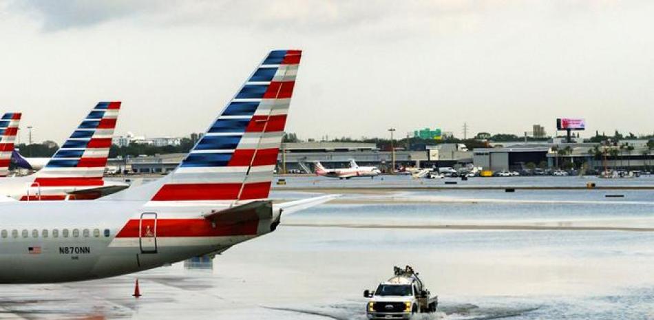Los aviones de American Airlines se sientan en la terminal mientras un camión atraviesa la pista inundada en el Aeropuerto Internacional de Fort Lauderdale-Hollywood el jueves, 13 de abril de 2023, Fort Lauderdale, Fla. (David Santiago/Miami Herald vía AP)
