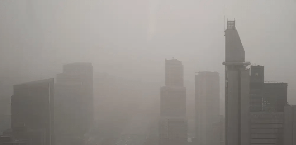 Edificios envueltos en una nube de polvo y arena en Beijing, el 11 de abril de 2023. (AP Foto/Mark Schiefelbein)