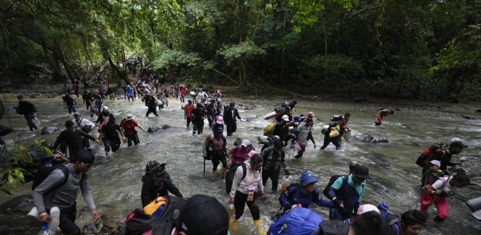 Migrantes, en su mayoría venezolanos, cruzan un río en la selva del Darién el 15 de octubre de 2022, en un recorrido de Colombia a Panamá, con la esperanza de seguir luego su viaje hacia Estados Unidos. La Agencia de la ONU para los Refugiados (ACNUR) y la Organización Internacional para las Migraciones (OIM) indicaron en un comunicado el jueves 13 de abril de 2023 que más 100.000 migrantes cruzaron esa ruta en los primeros meses del año y que, de seguir la tendencia, la cifra a final del año podría superar los 400.000. (AP Foto/Fernando Vergara, Archivo)
