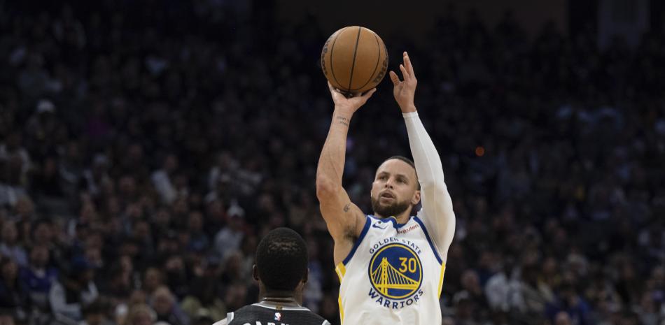 El base de los Warriors de Golden State Stephen Curry lanza el balón sobre el alero de los Kings de Sacramento Harrison Barnes e el encuentro del pasado 7 de abril.