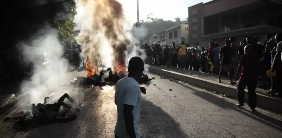 Un grupo de personas observa los cadáveres de presuntos pandilleros que fueron quemados vivos por una turba en la sección Canape Vert de Puerto Príncipe, Haití, el lunes 24 de abril de 2023.