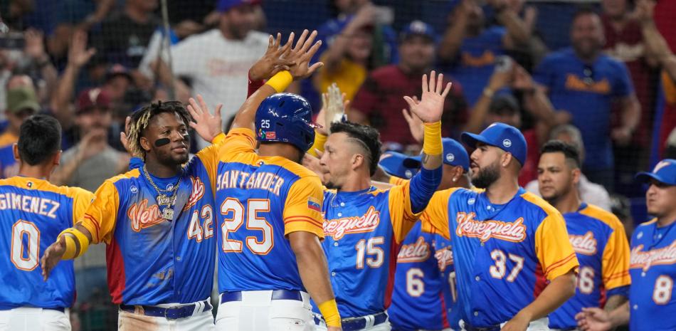 Anthony Santander (25) de Venezuela es felicitado por sus compañeros de equipo luego de anotar con un hit de Eugenio Suárez en la cuarta entrada de un juego del Clásico Mundial de Béisbol contra Venezuela, el martes 14 de marzo de 2023, en Miami. (Foto AP/Marta Lavandier)