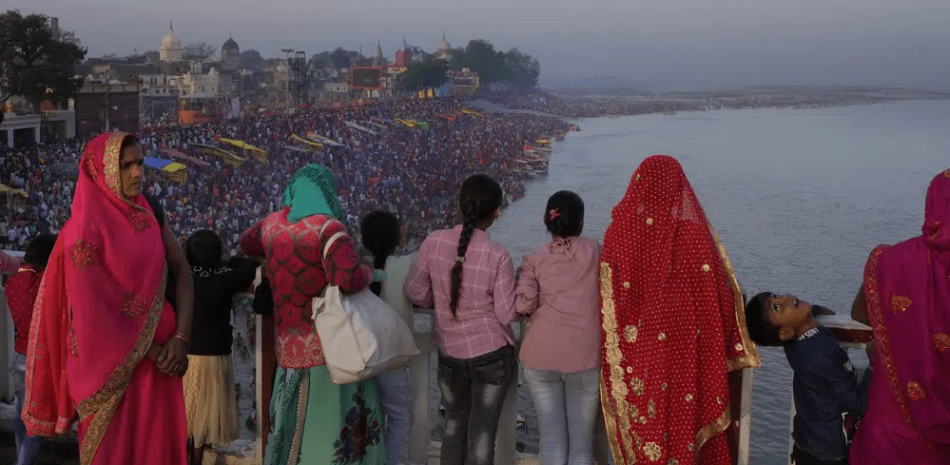 Familias observan desde un puente mientras miles de personas entran al río sagrado Saryu en Ayodhya, India, el 30 de marzo de 2023. (Foto AP /Manish Swarup)