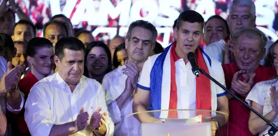 Santiago Peña, candidato presidencial del partido gobernante Colorado, a la derecha, habla junto al expresidente Horacio Cartes después del cierre de la votación durante las elecciones generales