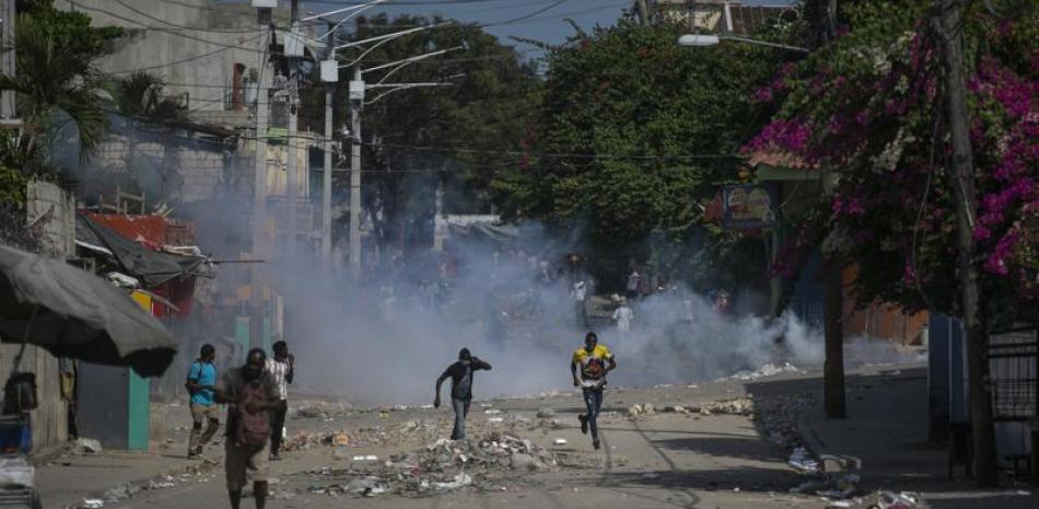 Manifestantes corren después de que la policía arrojara gases lacrimógenos durante una protesta para exigir la renuncia del primer ministro Ariel Henry, el lunes 3 de octubre de 2022, en la zona de Petion-Ville, en Puerto Príncipe, Haití.