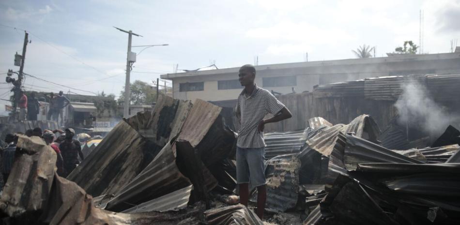 Un vendedor observa a los bomberos trabajar para extinguir un incendio en el mercado Shada en el área de Petion-ville en Puerto Príncipe, Haití, el jueves 4 de mayo de 2023.