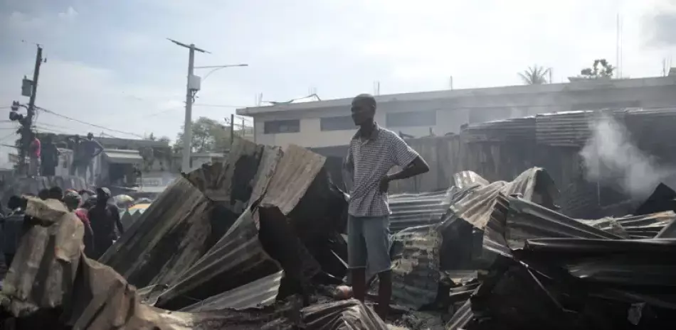 Un vendedor observa a los bomberos trabajar para extinguir un incendio en el mercado Shada en el área de Petion-ville en Puerto Príncipe, ayer.