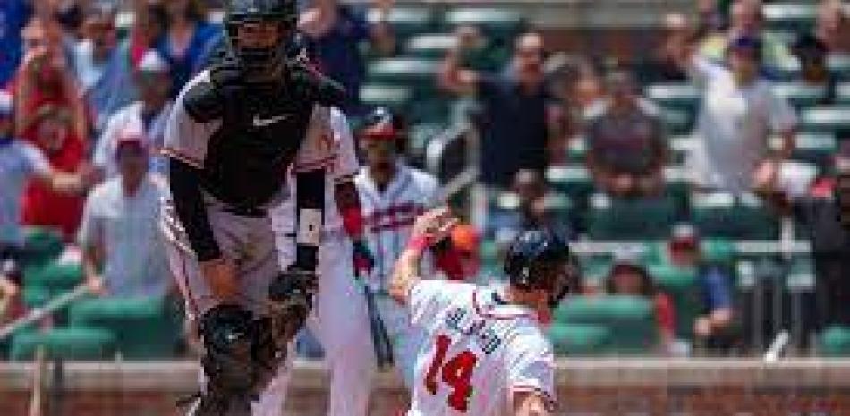 Sam Hilliard (14) de los Bravos de Atlanta se desliza en el plato en el 10mo inning del juego contra los Orioles de Baltimore.