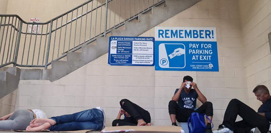 Grupo de migrantes, la mayoría provenientes de Venezuela, intentando descansar en un estacionamiento en Brownsville, Texas