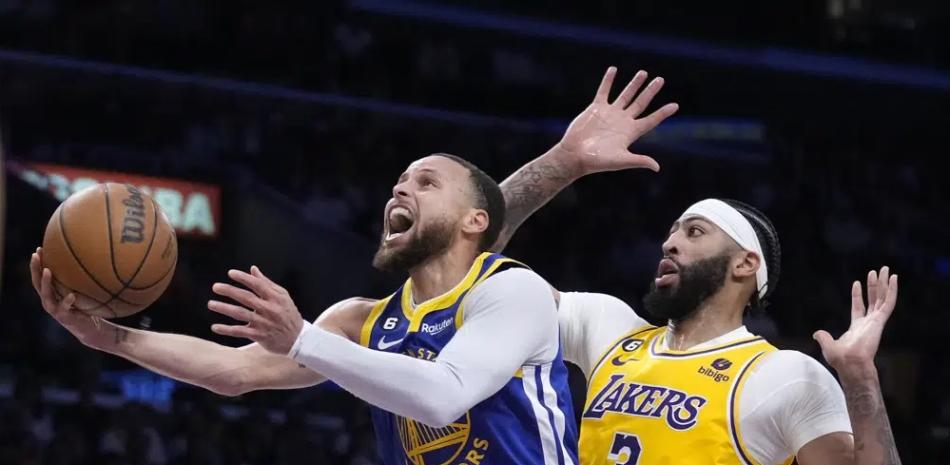 El jugador de los Warriors de Golden State Stephen Curry, a la izquierda, tira a canasta junto al jugador de los Lakers de Los Ángeles Anthony Davis.