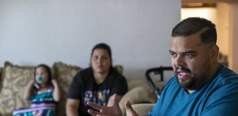El solicitante de asilo venezolano Luis López habla con The Associated Press mientras su esposa, Oriana Marcano, y su hija Amaloha López escuchan