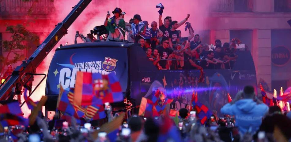 Los jugadores del equipo Barcelona celebran en un autobús durante un desfile para celebrar la victoria en La Liga en Barcelona, ​​España.