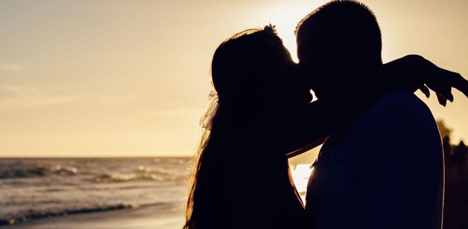 Silueta de pareja besándose en la playa.