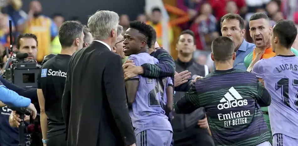 Vinicius Junior (centro) del Real Madrid pasa al lado de su técnico Carlo Ancelotti tras ser expulsado del partido contra el Valencia en la Liga de España, el domingo 21 de mayo de 2023.