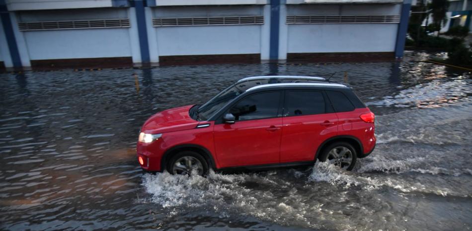 Un vehículo cruza por una calle inundada de agua en Santo Domingo