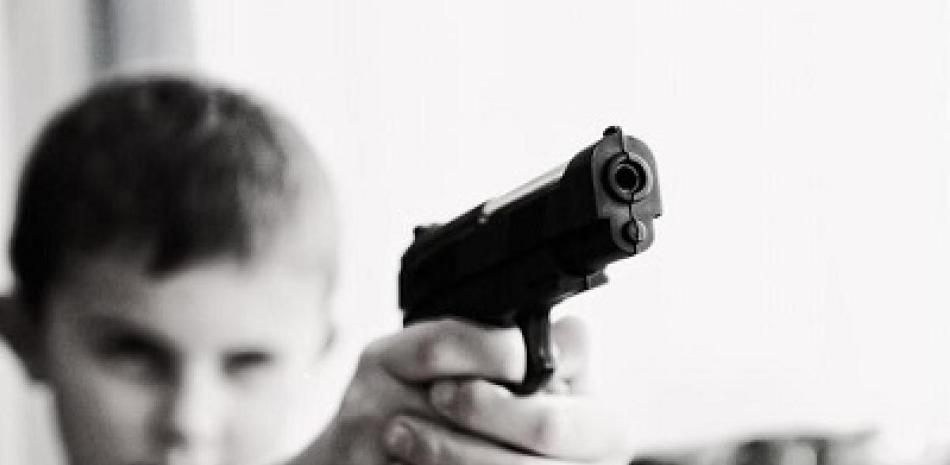 Menor de edad sosteniendo un arma de fuego. Imagen ilustrativa.